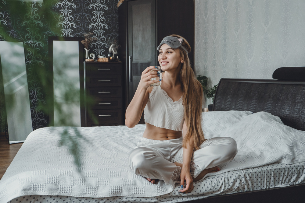 Self care, mourning routine, start day. Self Care Ideas for woman. Young woman lies on the bed and drinking water after waking up in the morning